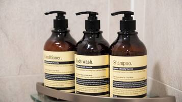 Trois bouteilles de gel douche, d’après-shampoing et de shampoing sont posées sur une étagère.