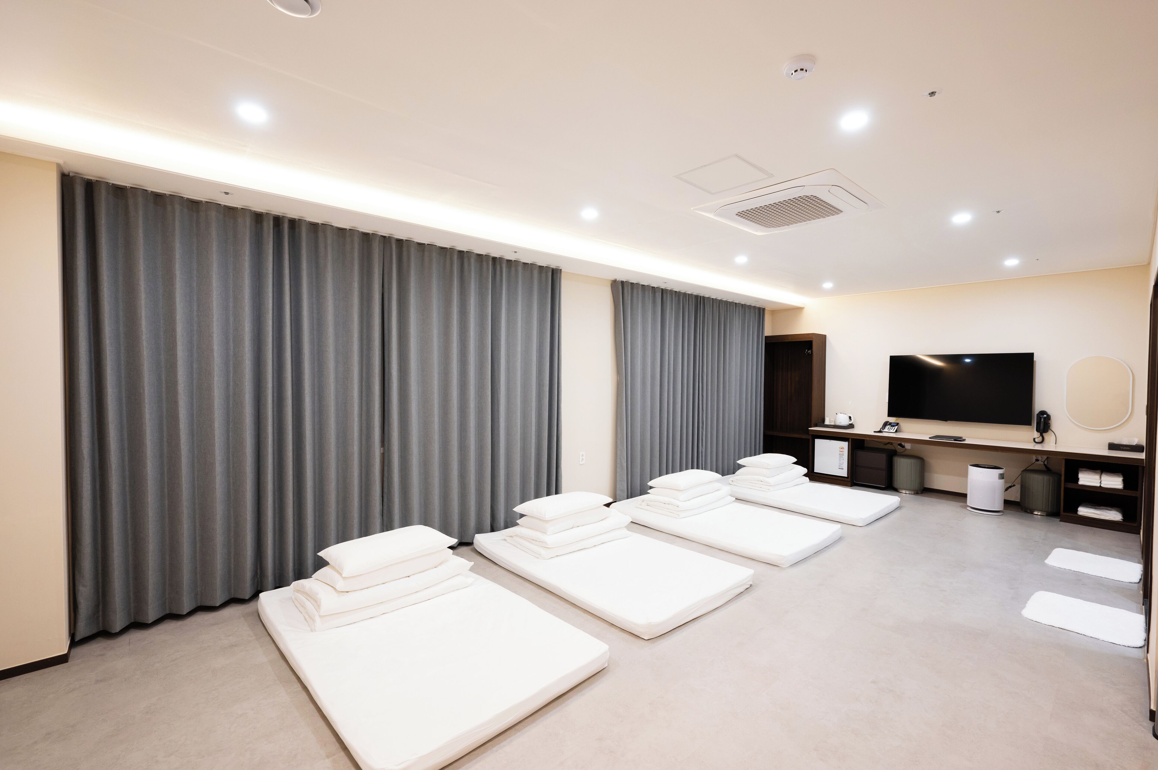 A room with multiple massage beds, a television, and a trash bin.
