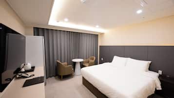 Une chambre d’hôtel moderne avec un grand lit, un bureau avec un ordinateur portable, une chaise et une petite table.