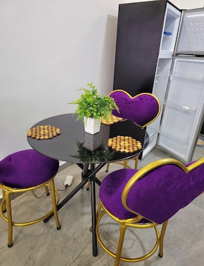 A round table with a potted plant and a plate of cookies, flanked by purple chairs with gold accents. - 1n2 bedroom w/gym 7 min walk to yaya and prestige mall, higher floor w/nice view (Nairobi)
