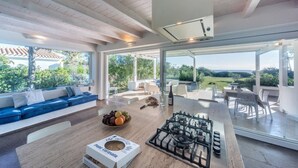 Cocina moderna con estufa a gas, una mesa de comedor y un rincón de estar con sofá azul y cojines blancos.
