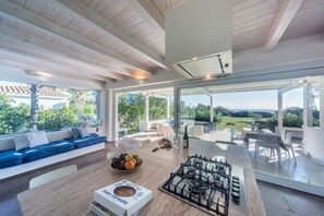 Eine moderne Küche mit Gasherd, einem Esstisch und einer Sitzecke mit blauem Sofa und weißen Kissen.