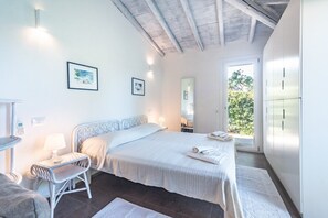 Ein Schlafzimmer mit Bett, Nachttisch, Stuhl und Blick auf Grün.