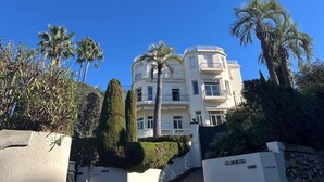 A multi-story building with balconies, surrounded by palm trees and well-maintained hedges. - Cannes Californie: elegant flat with sea view, parking and beach nearby. (Cannes)