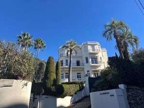 A multi-story building with balconies, surrounded by palm trees and well-maintained hedges. - Cannes Californie: elegant flat with sea view, parking and beach nearby. (Cannes)