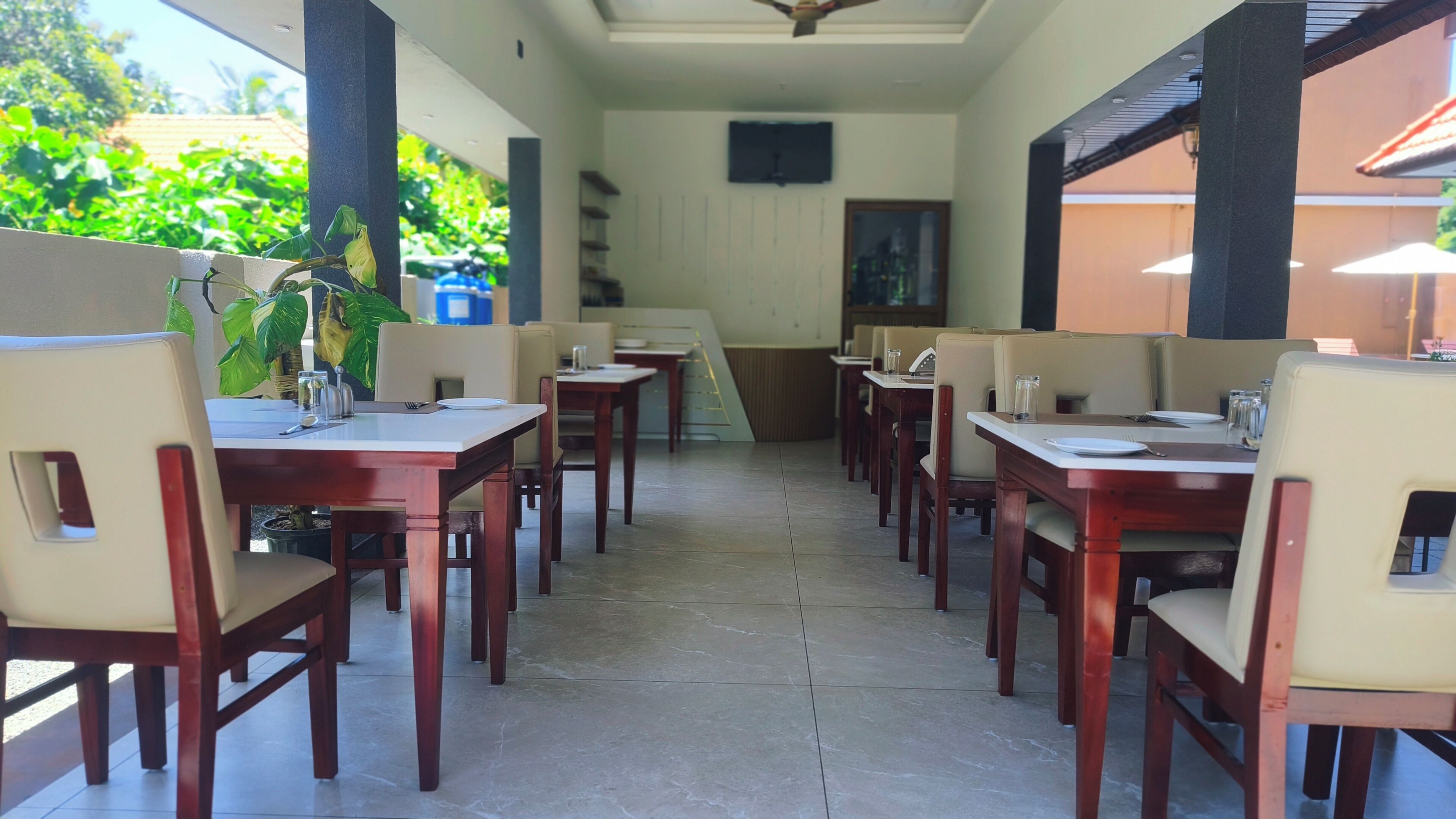 A restaurant with multiple tables and chairs, a tiled floor, and a ceiling fan.