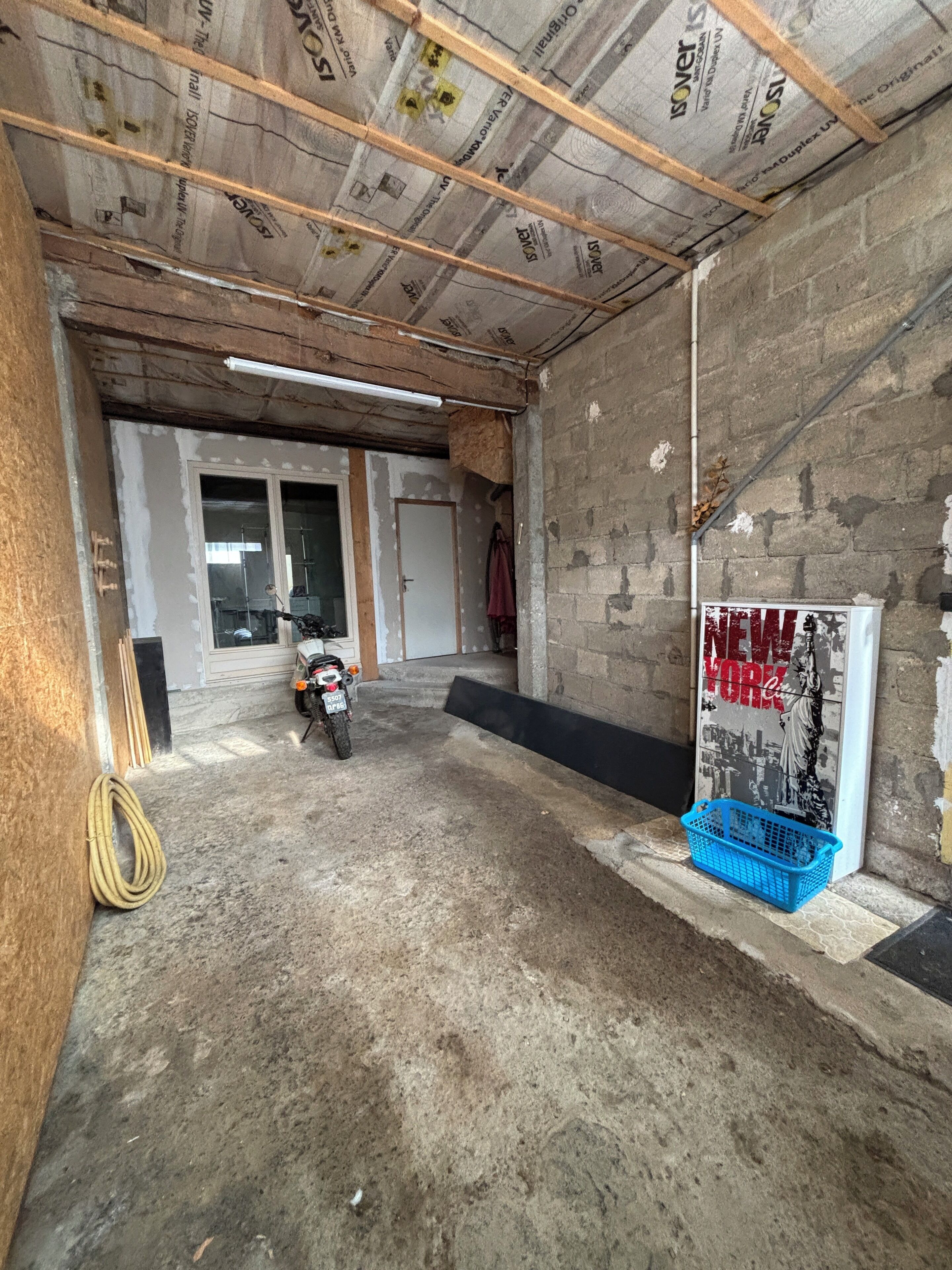 A construction site with exposed ceiling and walls, a motorcycle, and a poster of the Statue of Liberty.