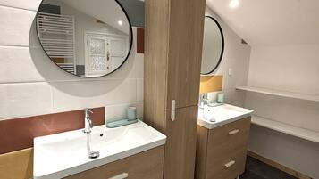 A modern bathroom with two sinks, wooden cabinets, and a large mirror.