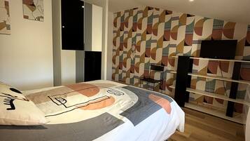 A bedroom with a bed, a television, and a patterned wall.