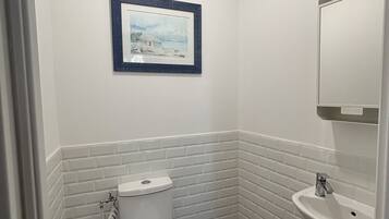 A small bathroom with a toilet, sink, and a framed picture on the wall.