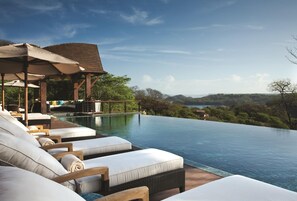 An infinity pool with lounge chairs, a wooden pergola, and a view of the landscape. - Four Seasons Resort Costa Rica At Peninsula Papaga (Nacascolo)