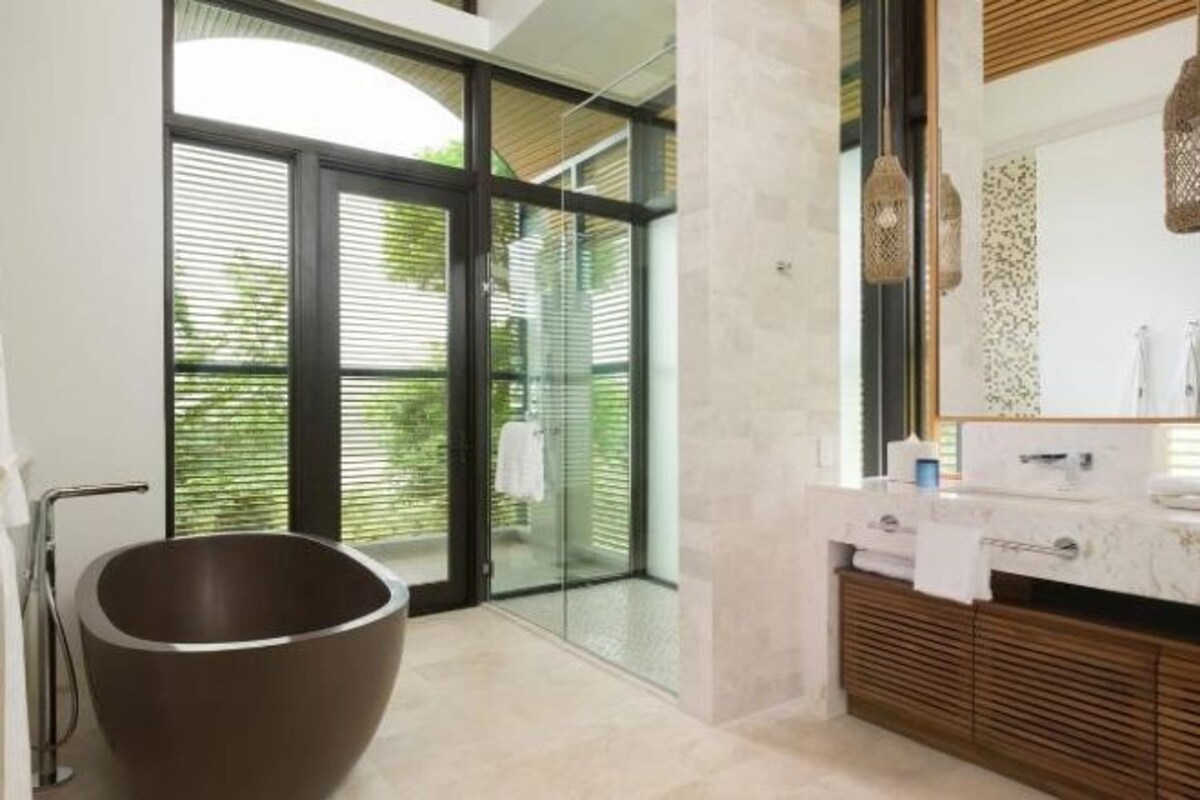 Un baño moderno con una bañera independiente grande, una zona de ducha con mampara de vidrio y un tocador con espejo.