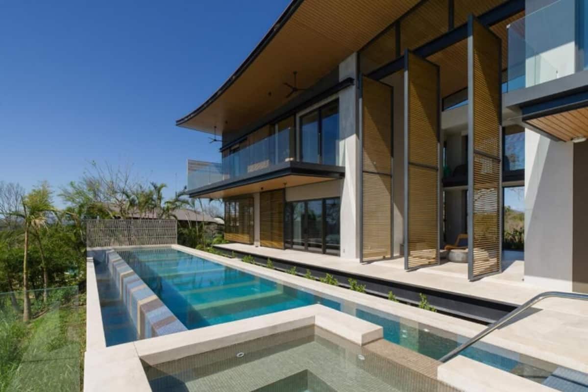 Een modern herenhuis met zwembad, grote ramen en een balkon.