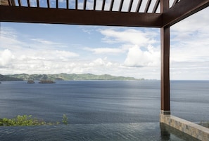 A view from a covered outdoor area with a pool, overlooking a calm sea and distant land. - Four Seasons Resort Costa Rica At Peninsula Papaga (Nacascolo)