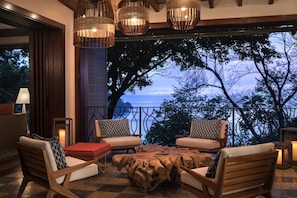 A terrace with wooden furniture, a large table, and hanging lights.
