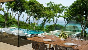 A dining area with a view of the ocean, a glass-enclosed pool, and lush greenery. - Four Seasons Resort Costa Rica At Peninsula Papaga (Nacascolo)