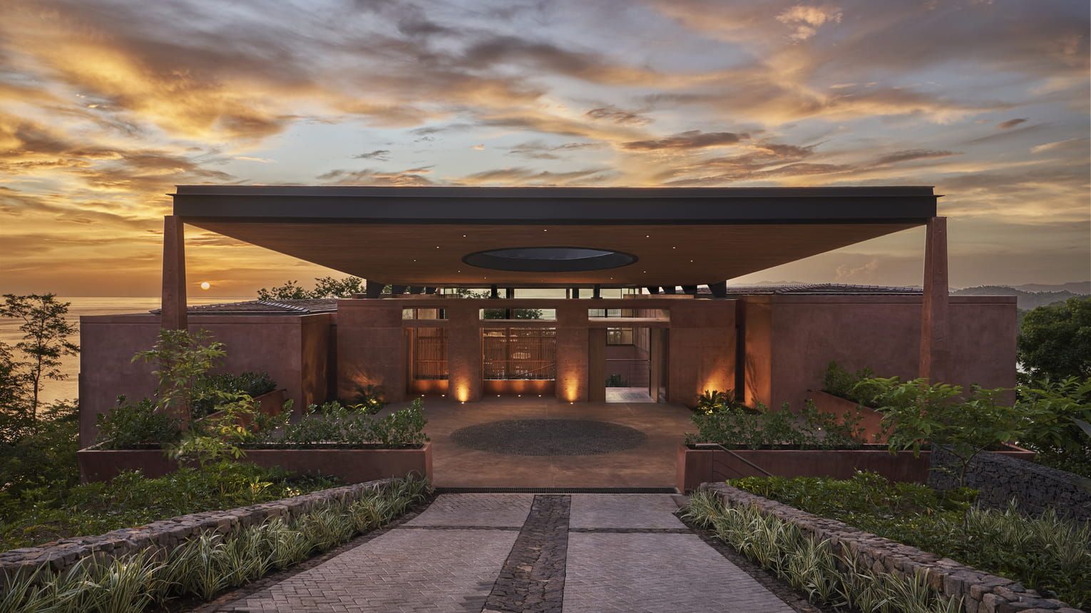 A modern building with a covered entrance, a central circular feature, and a landscaped garden.