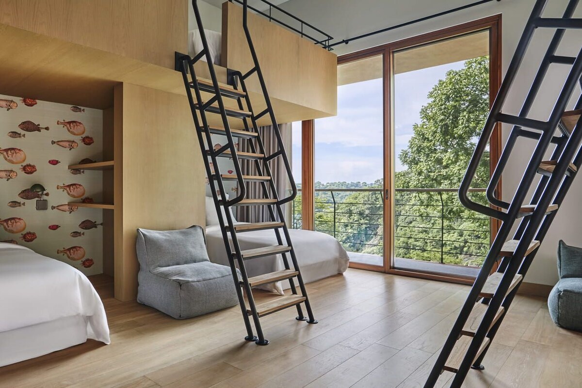 Ein Schlafzimmer mit Hochbett, einer Leiter, einer Couch und einem großen Fenster mit Blick.