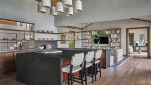A modern kitchen with a central island, bar stools, and a bookshelf. - Four Seasons Resort Costa Rica At Peninsula Papaga (Nacascolo)