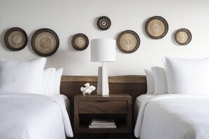 A hotel room with two beds, a bedside table with a lamp, and decorative woven wall hangings. - Four Seasons Resort Costa Rica At Peninsula Papaga (Nacascolo)