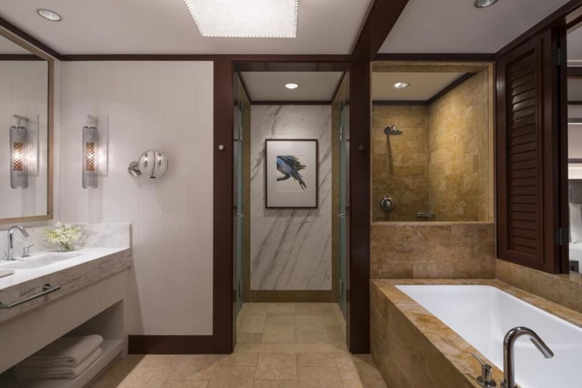 Ein modernes Badezimmer mit einer großen Badewanne, einem Doppelwaschtisch und einem gerahmten Kunstwerk an der Wand.