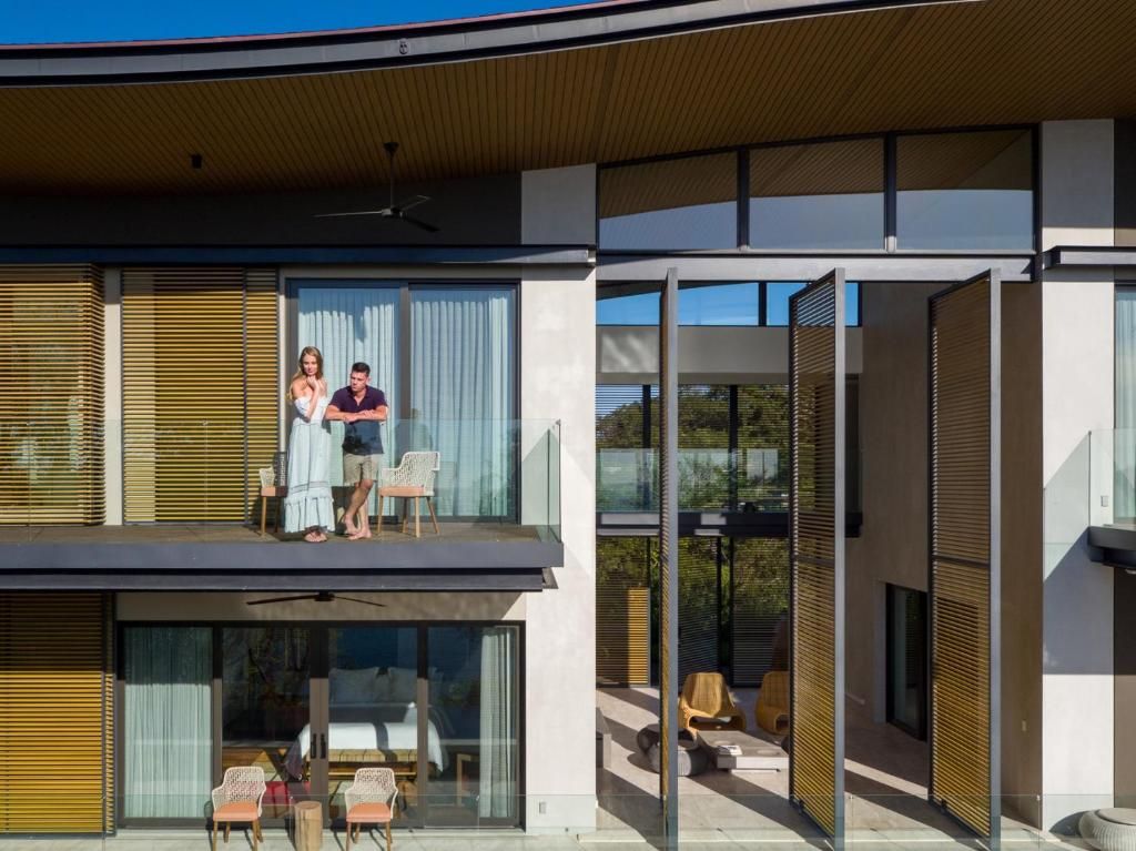 A modern building with a balcony, large windows, and a covered outdoor seating area.