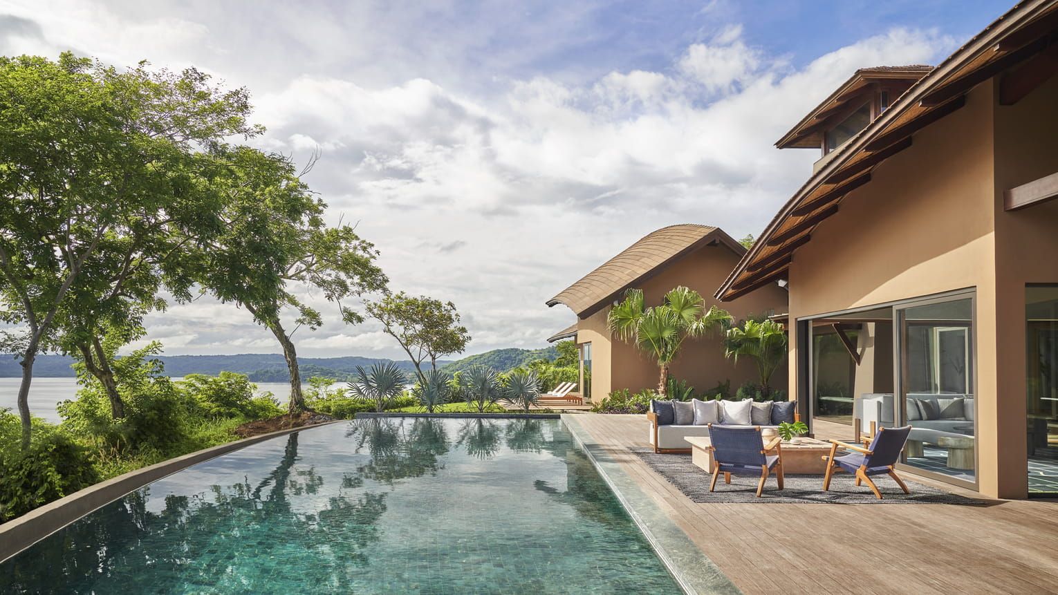 Ein modernes Resort mit einem klaren Infinity-Pool, Sitzgelegenheiten im Freien und Blick auf die Berge.