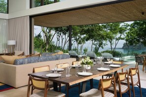 A modern dining area with a large table set for six, surrounded by chairs, and a sofa with patterned cushions. - Four Seasons Resort Costa Rica At Peninsula Papaga (Nacascolo)