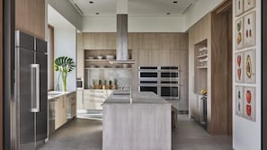 A modern kitchen with a central island, stainless steel appliances, wooden cabinetry, and a plant.