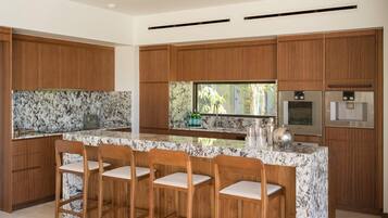 Una cocina moderna con armarios de madera, encimera de mármol y una barra con taburetes.