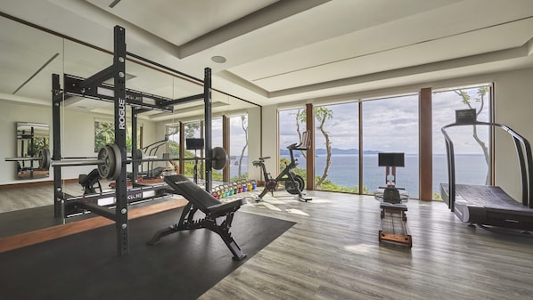 A spacious gym with a weightlifting area, cardio machines, and a treadmill.