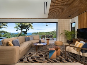 A modern living room with a sofa, coffee table, and TV, overlooking a scenic view. - Four Seasons Resort Costa Rica At Peninsula Papaga (Nacascolo)