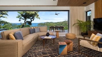 A modern living room with a large window, a sofa, a coffee table, and a TV.