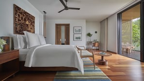 Un dormitorio moderno con cama, mesitas de noche, ventilador de techo, ventana grande y vistas al exterior.