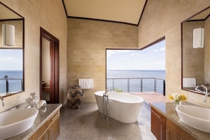A modern bathroom with a freestanding bathtub, two sinks, a large mirror, and a view of the sea. - Four Seasons Resort Costa Rica At Peninsula Papaga (Nacascolo)