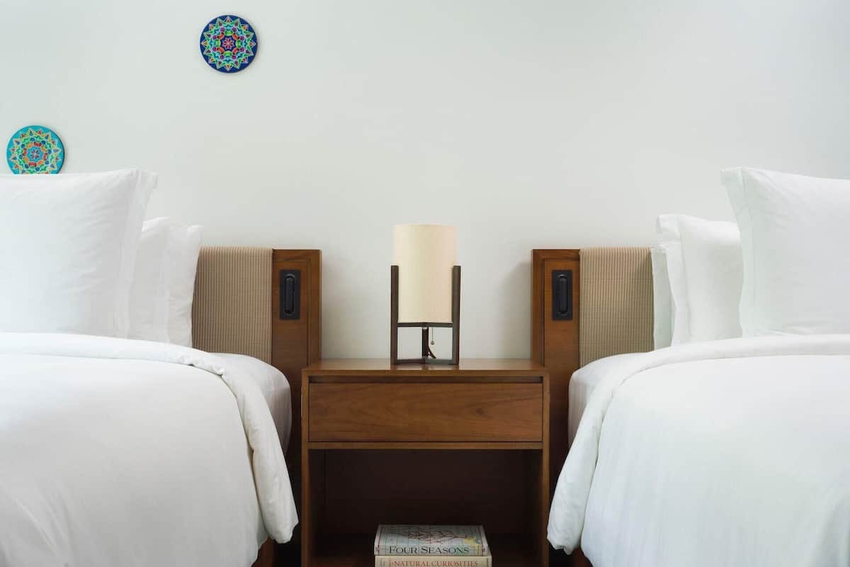 Een hotelkamer met twee bedden, een nachtkastje, een lamp en twee decoratieve wandplaten.