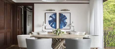 Un comedor con una mesa redonda, cuatro sillas, dos lámparas de pared y dos obras de arte enmarcadas.
