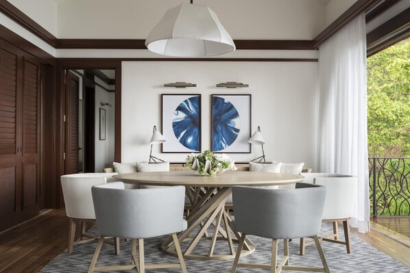 A dining area with a round table, four chairs, two wall-mounted lamps, and two framed artworks. - Four Seasons Resort Costa Rica At Peninsula Papaga (Nacascolo)