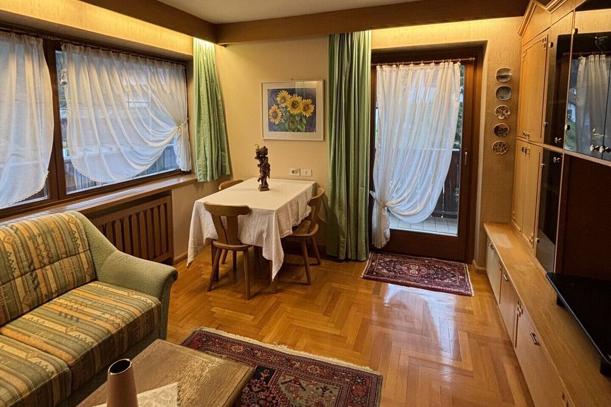 A cozy living room with a sofa, a dining table, and a TV cabinet.
