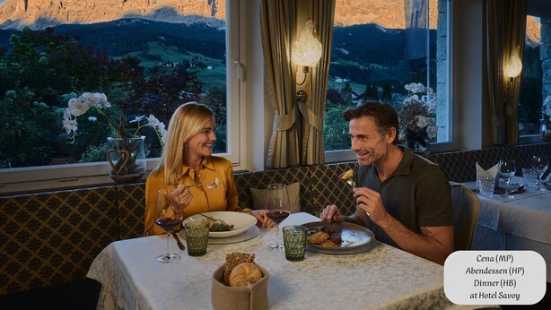 A dining table with a view of mountains, a candle, and a vase with flowers. - Ciasa Nives (Badia)
