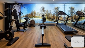 A gym with treadmills, a stationary bike, and weight machines. There's a large window with a view of trees and a snowy landscape. - Ciasa Nives (Badia)