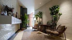 A modern interior with a herringbone floor, a wooden dining table, and a comfortable seating area. - Westminster Fire Station Comfort Apartments (London)