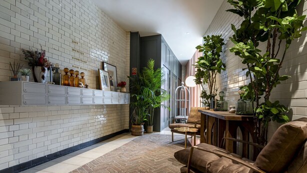 A modern interior with a herringbone floor, white brick walls, and a wooden bench. - Westminster Fire Station Comfort Apartments (London)