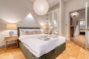 A bedroom with a large bed, two bedside tables, a hanging light fixture, and a wardrobe. - Westminster Fire Station Chic Apartments (London)