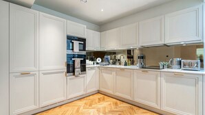 Een moderne keuken met witte kasten, een visgraat houten vloer en roestvrijstalen apparatuur.