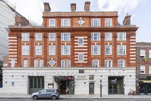 A red brick building with a white facade, a fire brigade station sign, and a flower arrangement at the entrance. - Westminster Fire Station Chic Apartments (London)