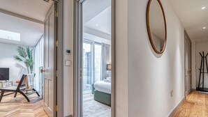 Une chambre d’hôtel moderne avec un plancher en bois, un grand miroir et une vue sur la ville grâce à de grandes fenêtres.