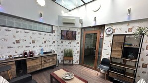 A modern kitchen with a built-in oven, a coffee machine, and a sink. There is a dining area with a wooden table and chairs.
