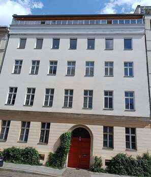A multi-story building with a red door, multiple windows, and a visible entrance. - Studio Berlin Center (Berlin)