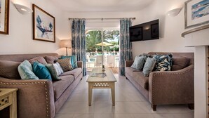 Ein Wohnzimmer mit zwei Sofas, einem Couchtisch und einem an der Wand befestigten Fernseher.